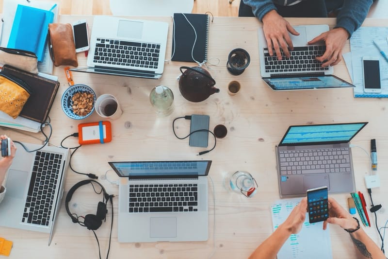 Overhead view of busy workspace with multiple laptops and team members working